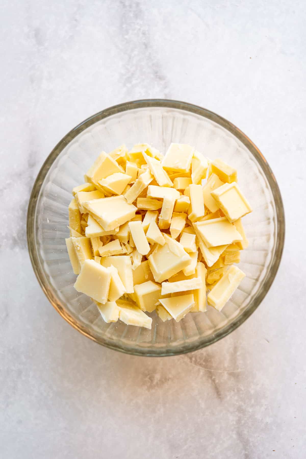 Chopped white chocolate in a glass bowl.