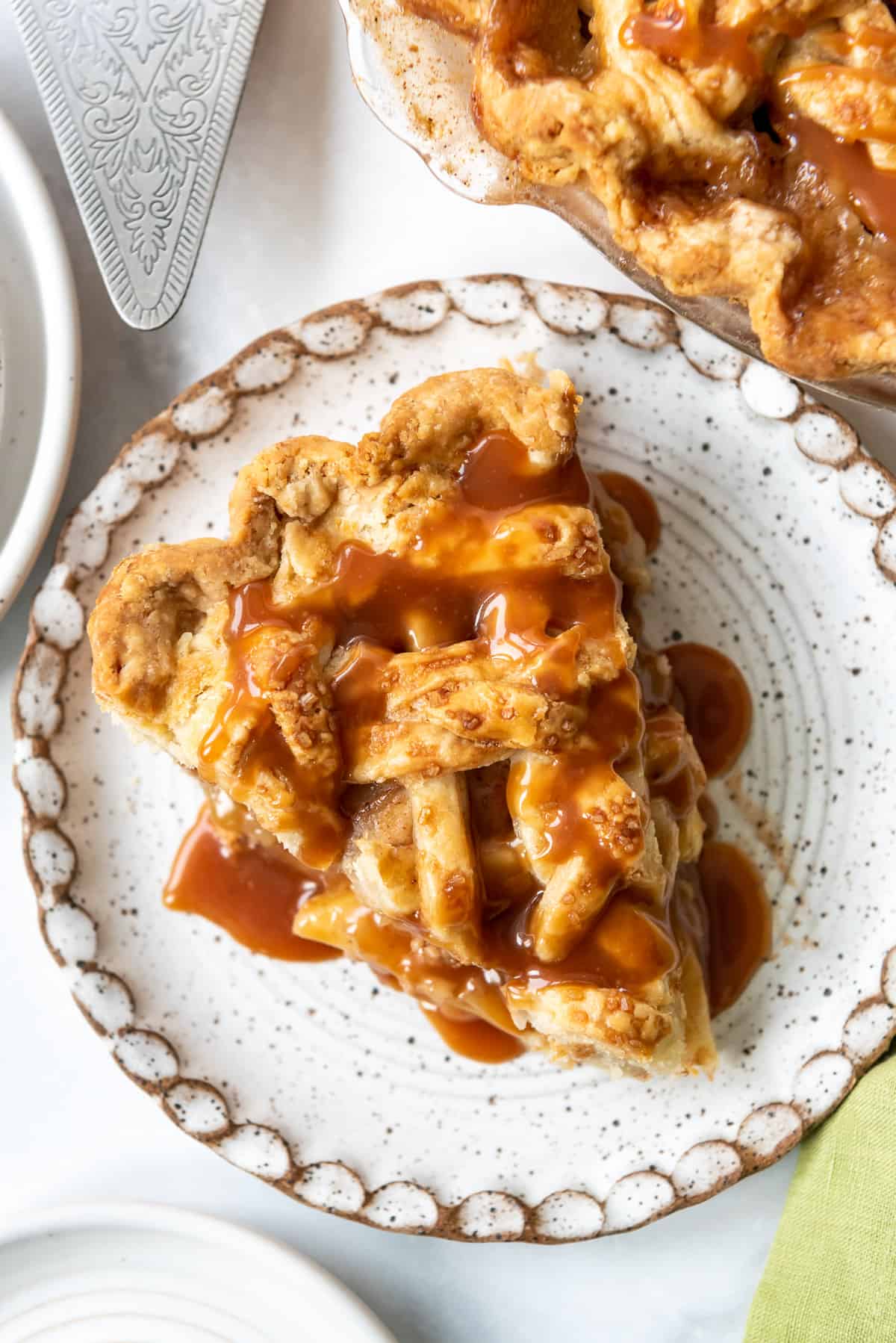 A slice of apple pie with caramel drizzled on top.