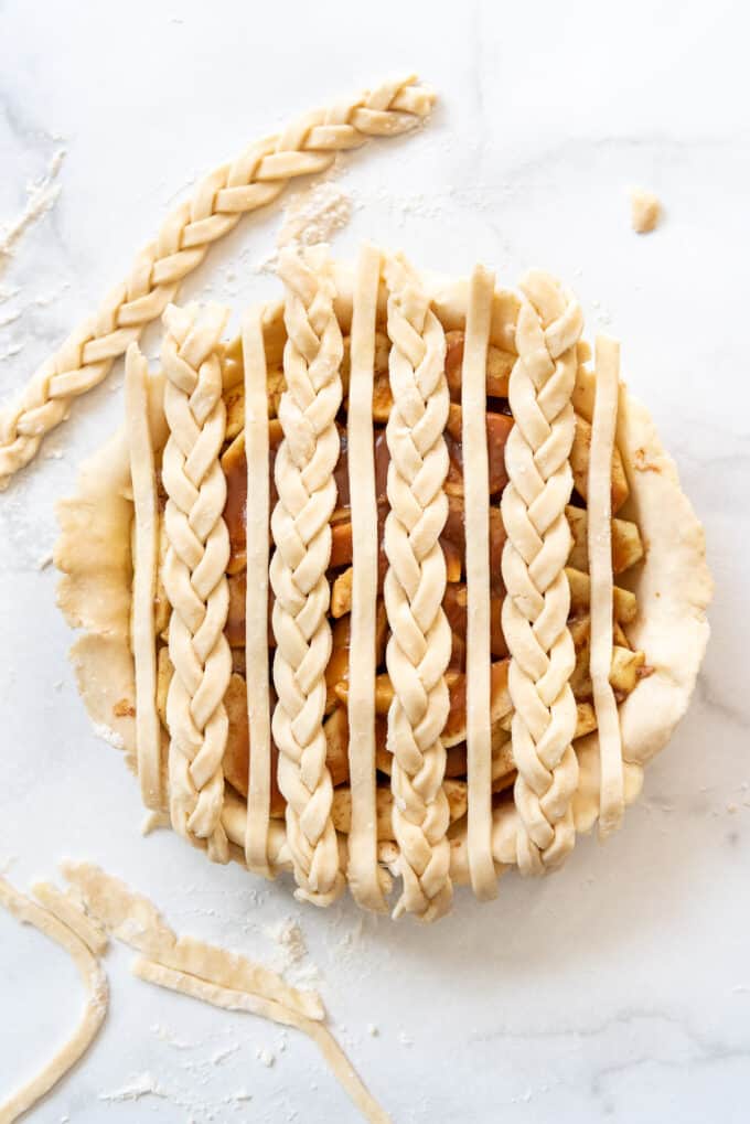 Adding braided strips of pie crust to a caramel apple pie.