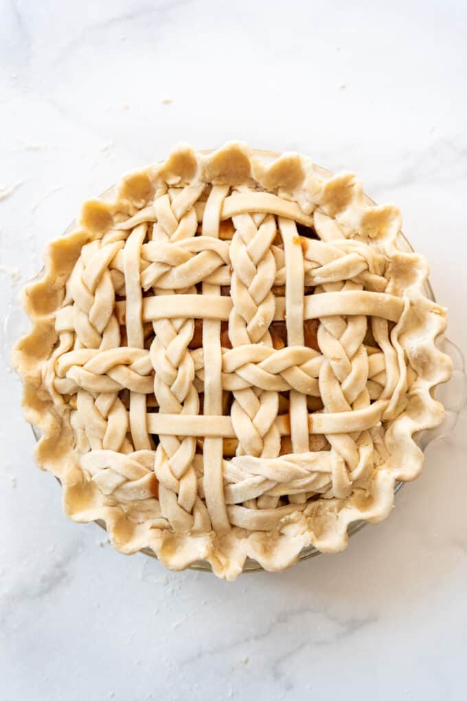 An unbaked caramel apple pie with a braided lattice crust.