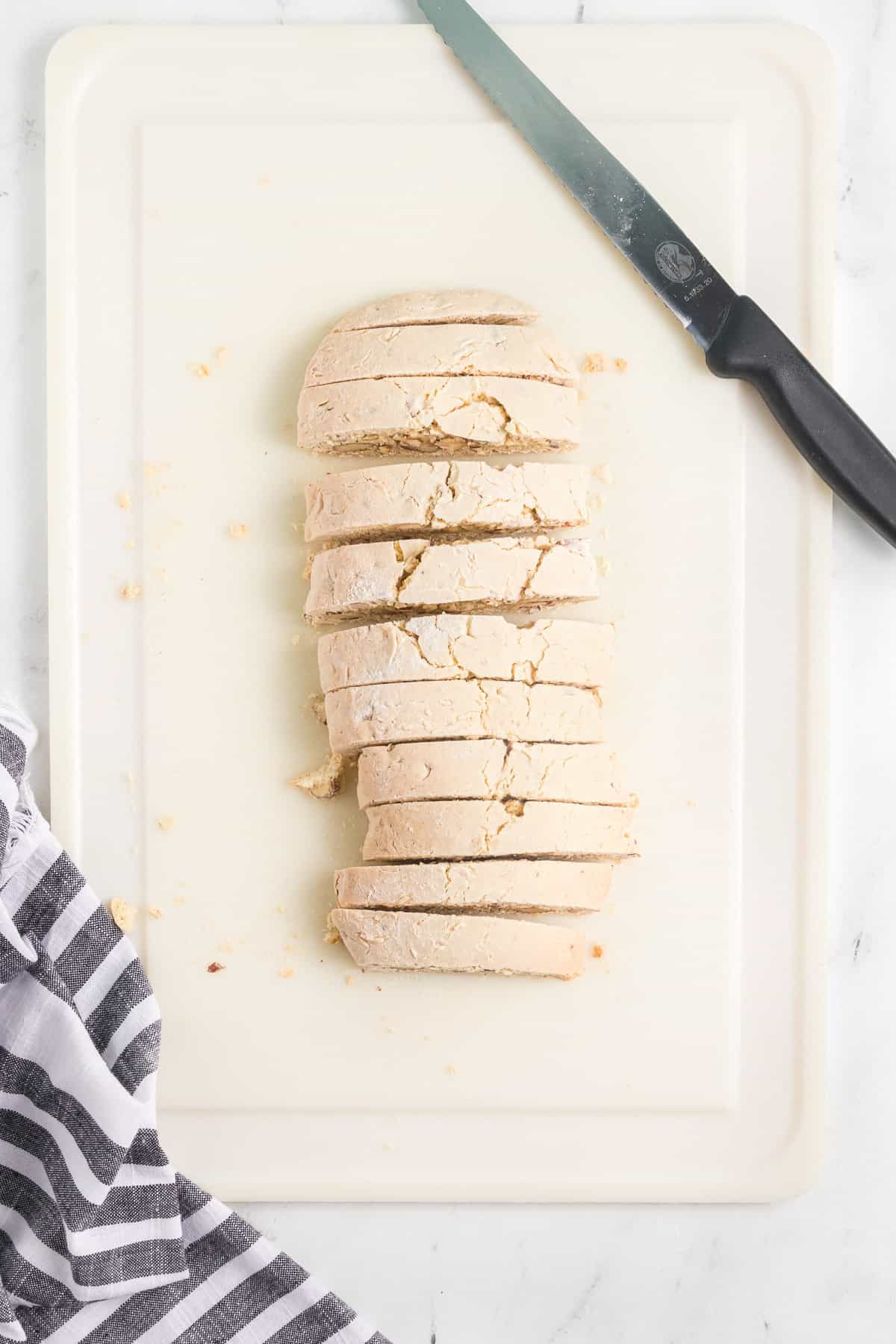 Cutting baked biscotti into individual cooking with a serrated knife.