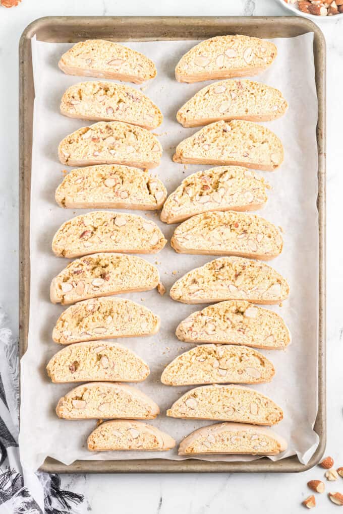 Sliced almond biscotti on a baking sheet lined with parchment paper.