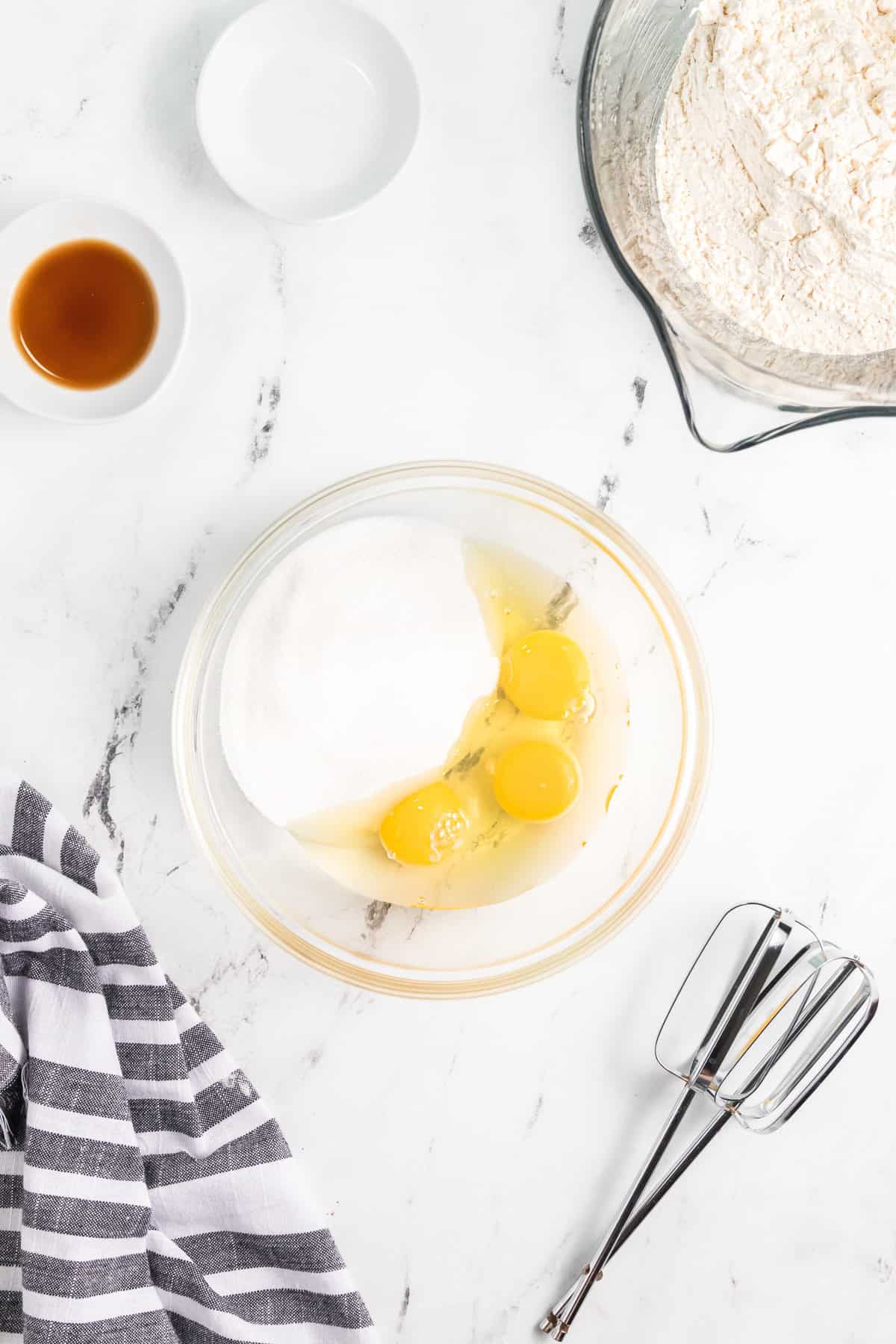 Eggs and granulated sugar in a glass mixing bowl.