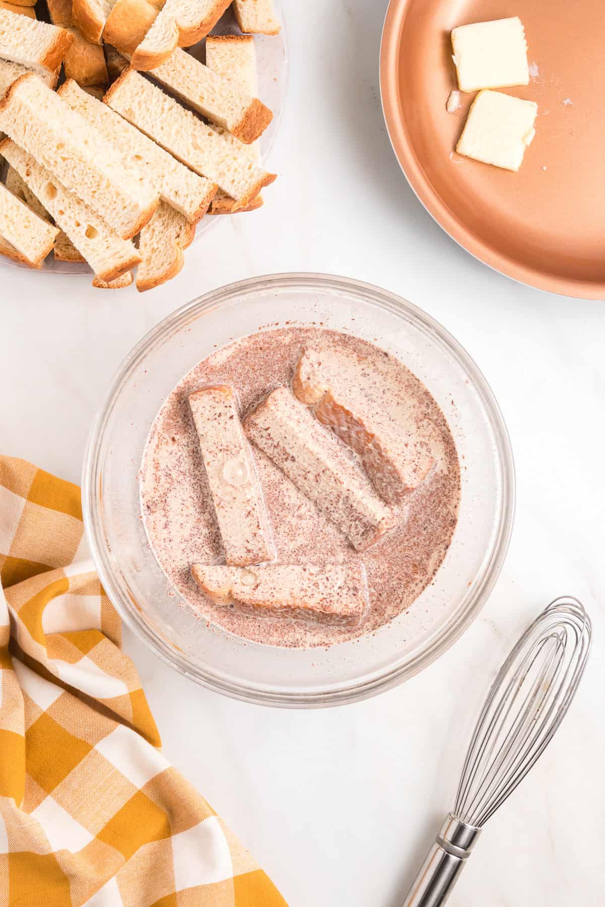 Soaking rectangles of bread in an egg custard mixture.