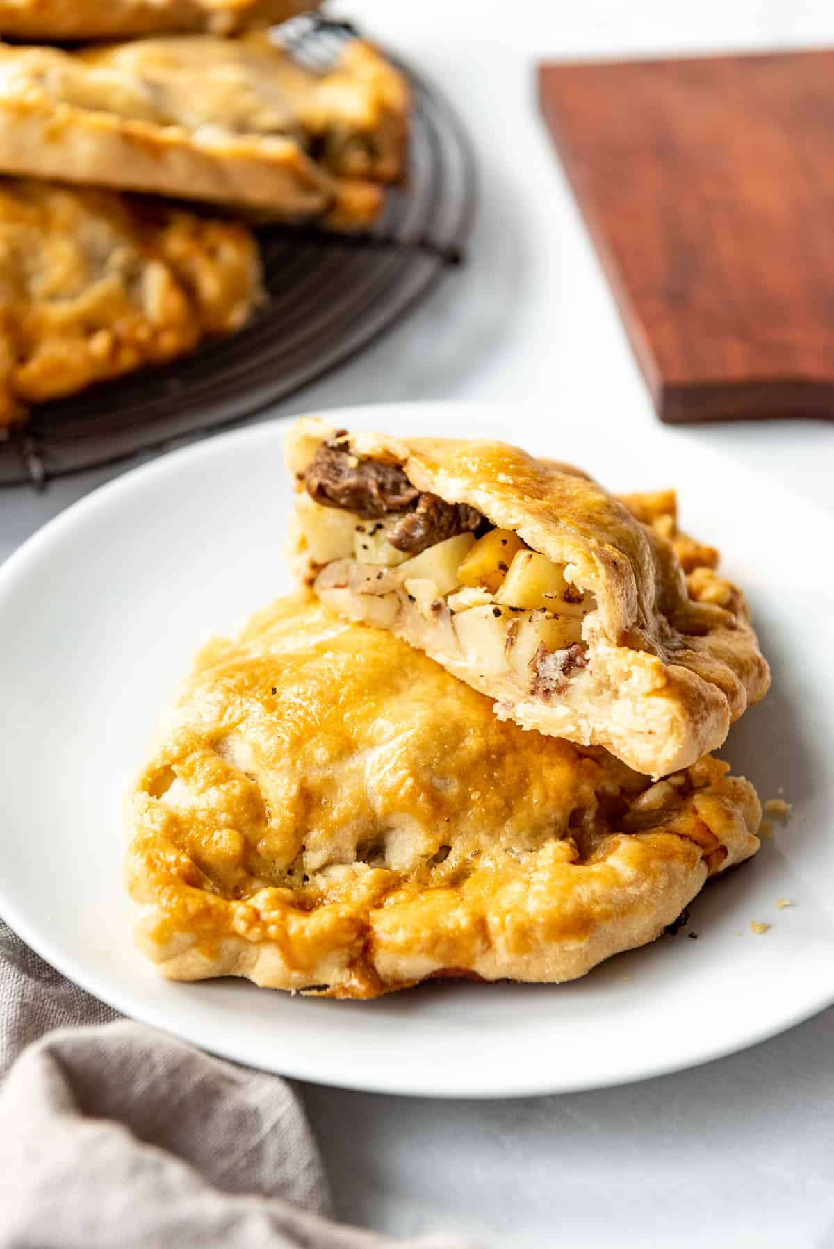 Two halves of a cornish pasty on a white plate.