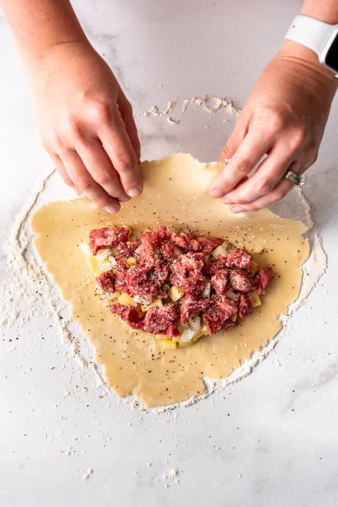 Folding pastry dough over a meat, potato, and rutabaga filling.