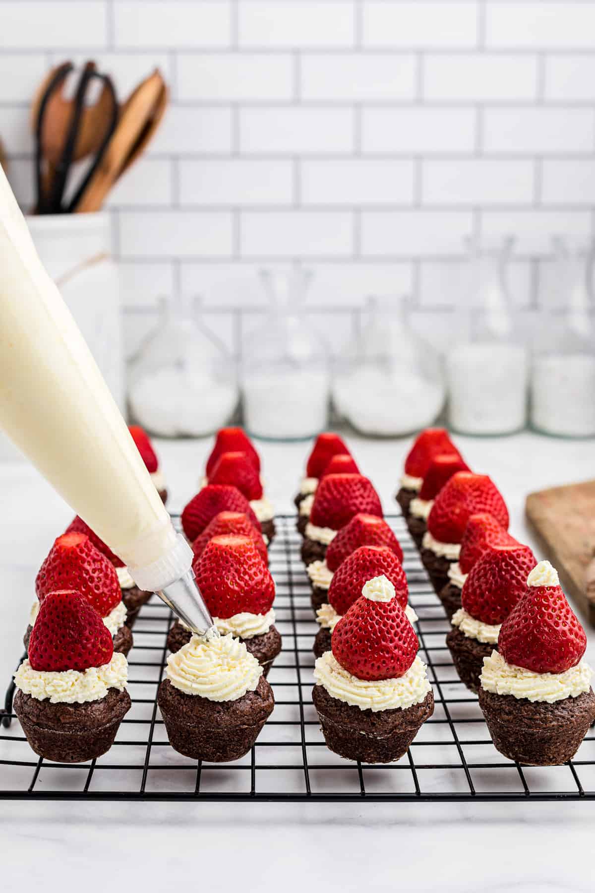 Piping whipped cream onto brownie bites.