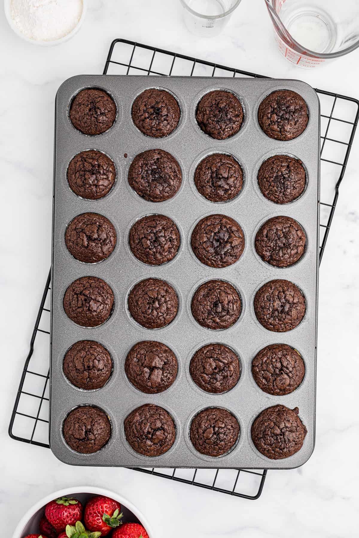 Baked mini brownie bites cooling in the pan on a wire rack.