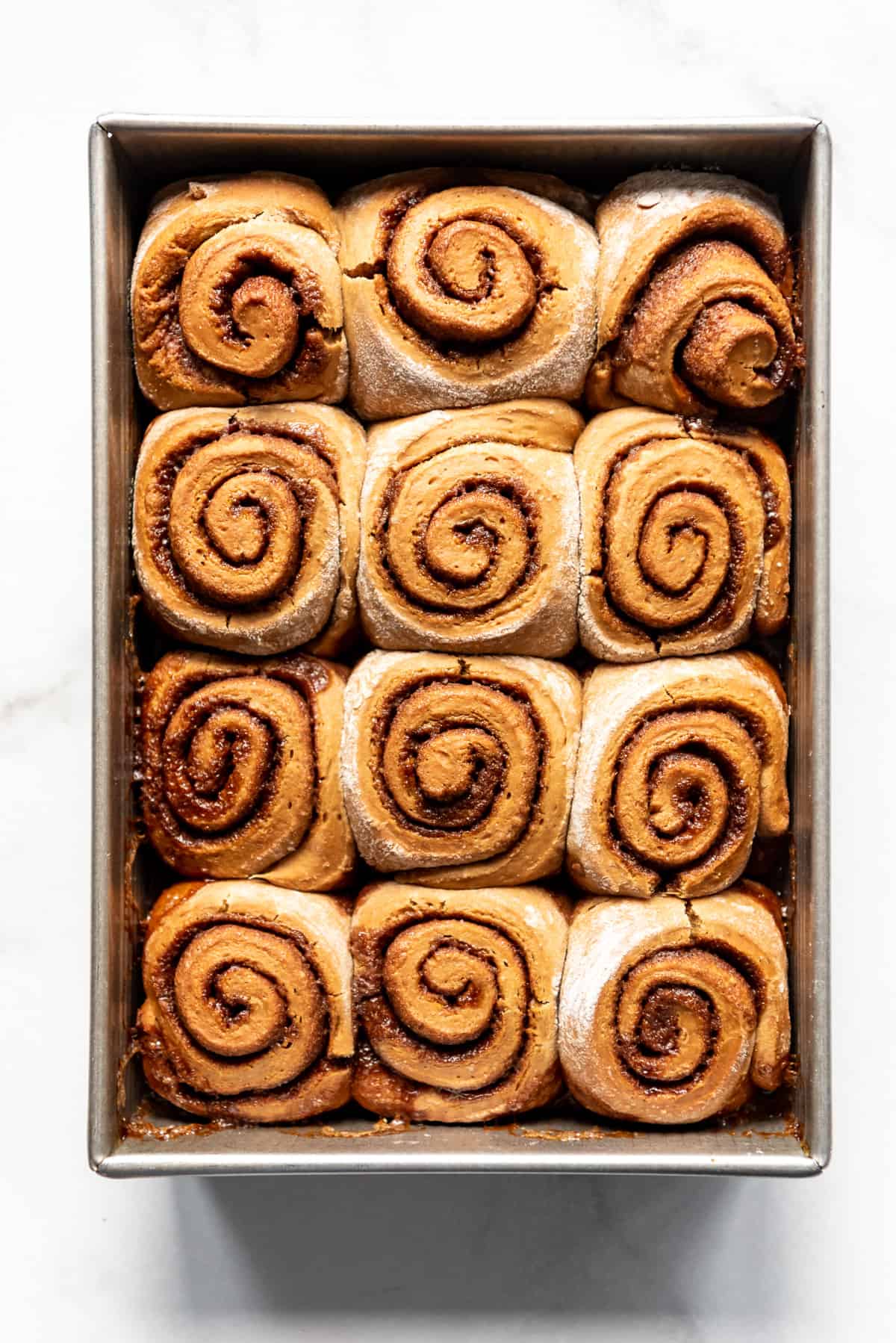 Baked gingerbread cinnamon rolls in a pan.