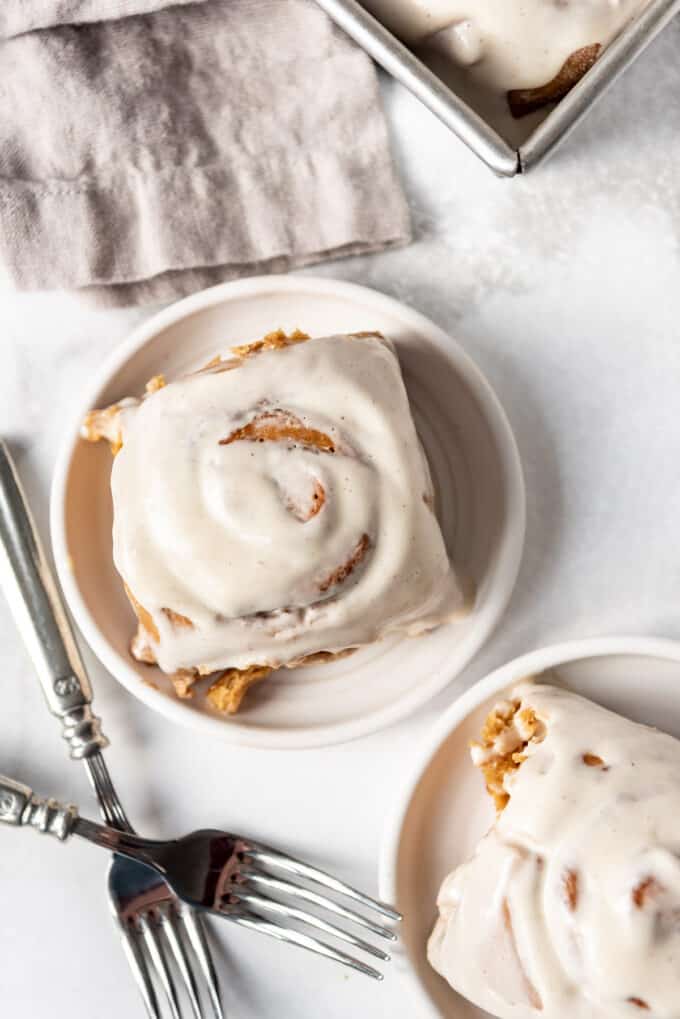 Homemade frosted cinnamon rolls on a plate.