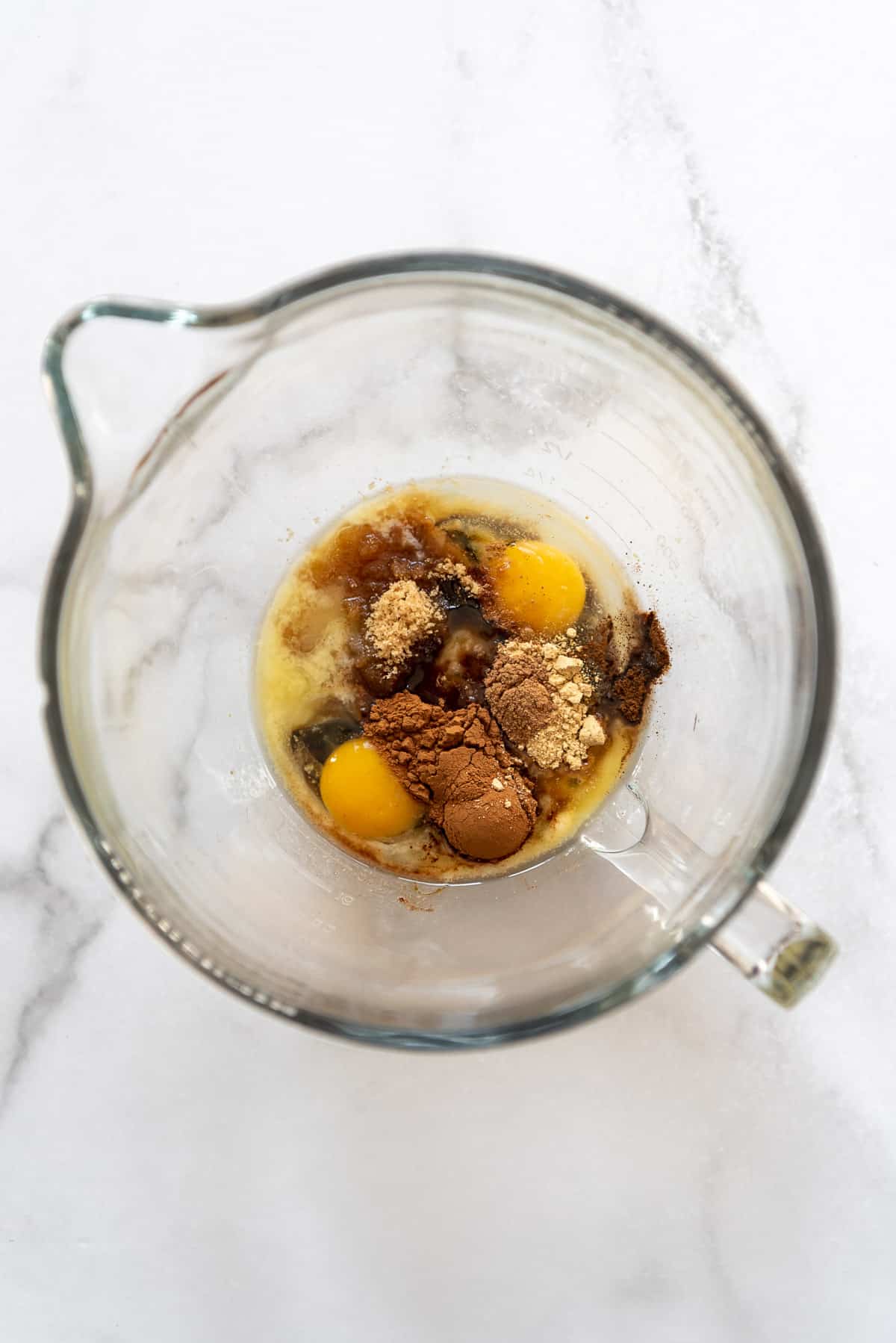 Eggs, melted butter, cinnamon and gingerbread spices, and brown sugar in a large glass bowl.