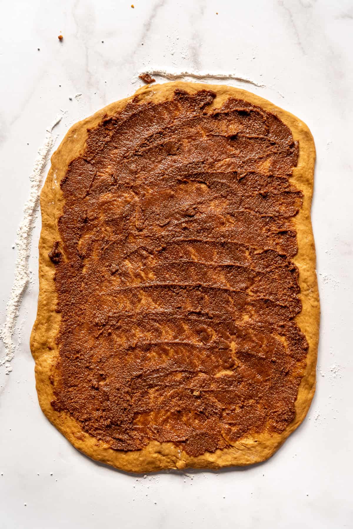 Spreading cinnamon and molasses filling on gingerbread spiced sweet yeast dough.