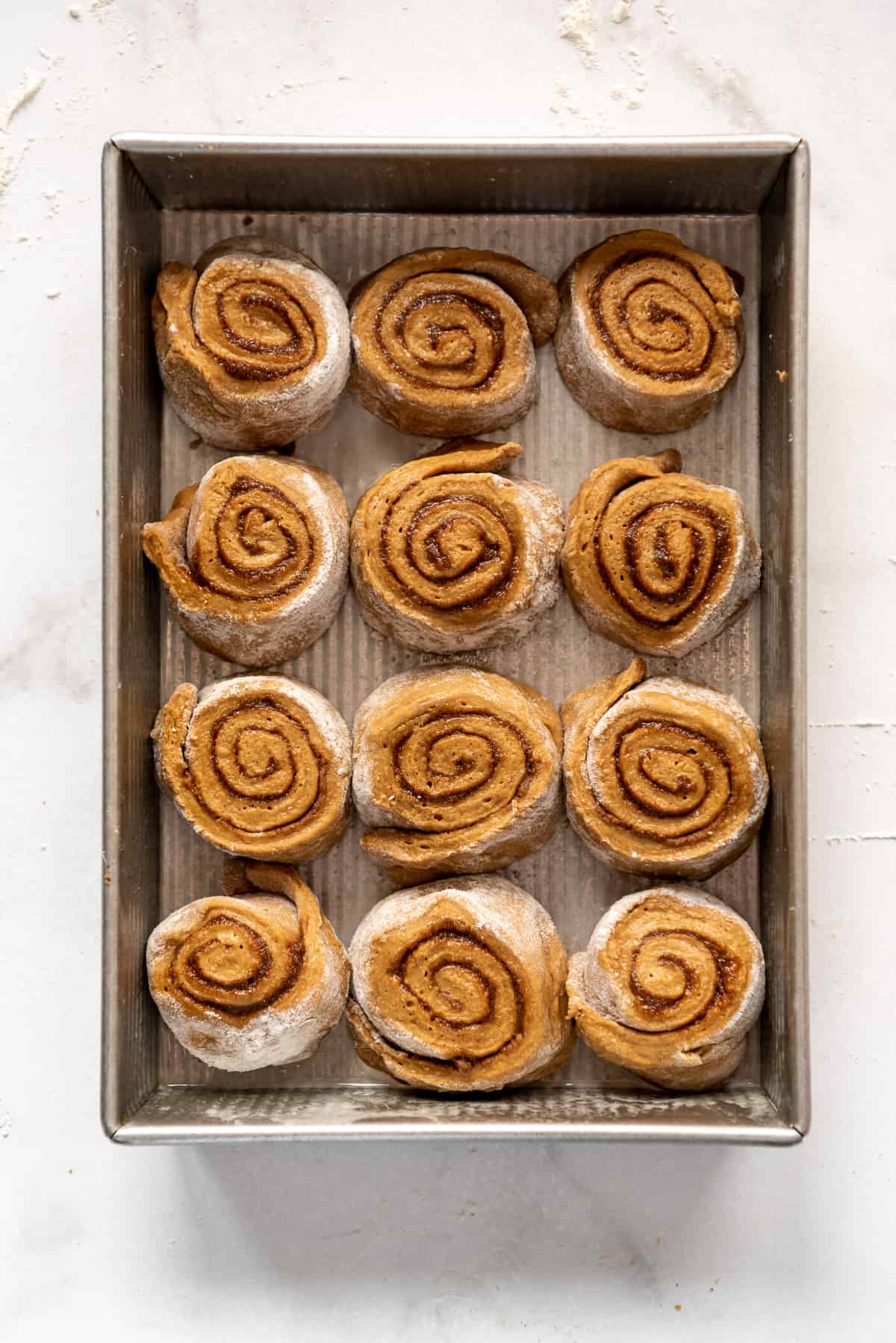 Unproofed gingerbread cinnamon roll dough in a 9x13-inch pan.