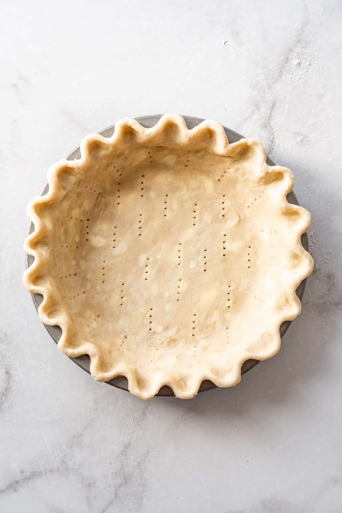 An unbaked pie crust that has been pricked all over with the tines of a fork.
