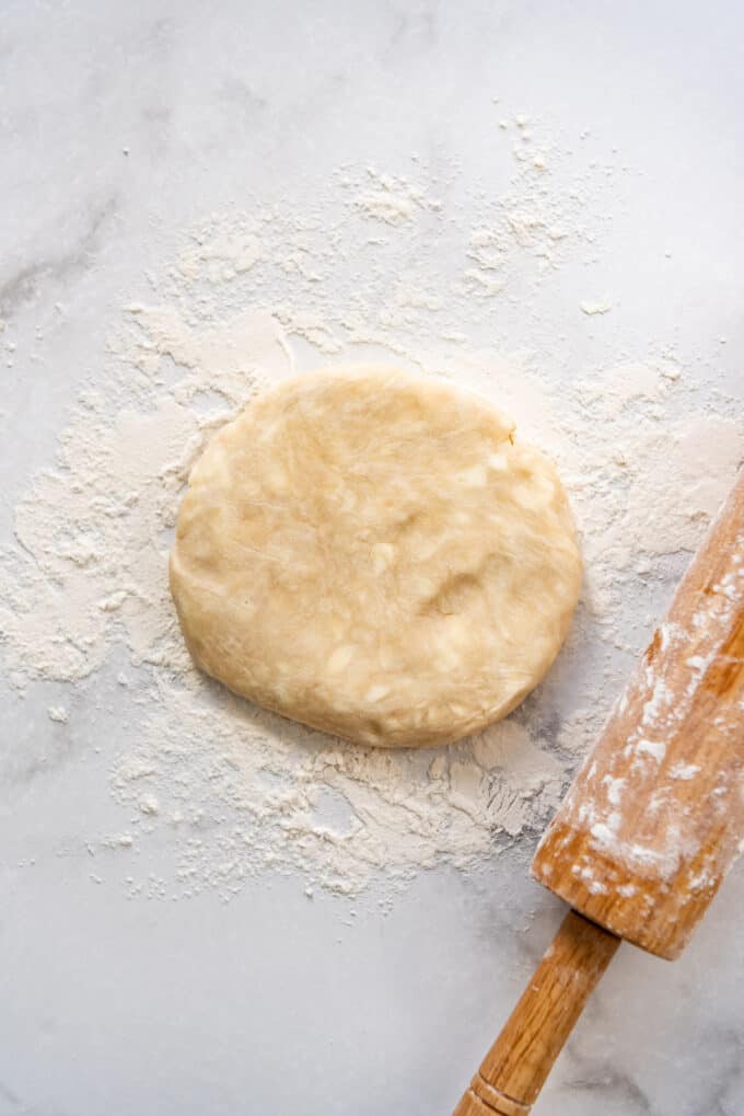 A disc of pie dough on a floured surface.