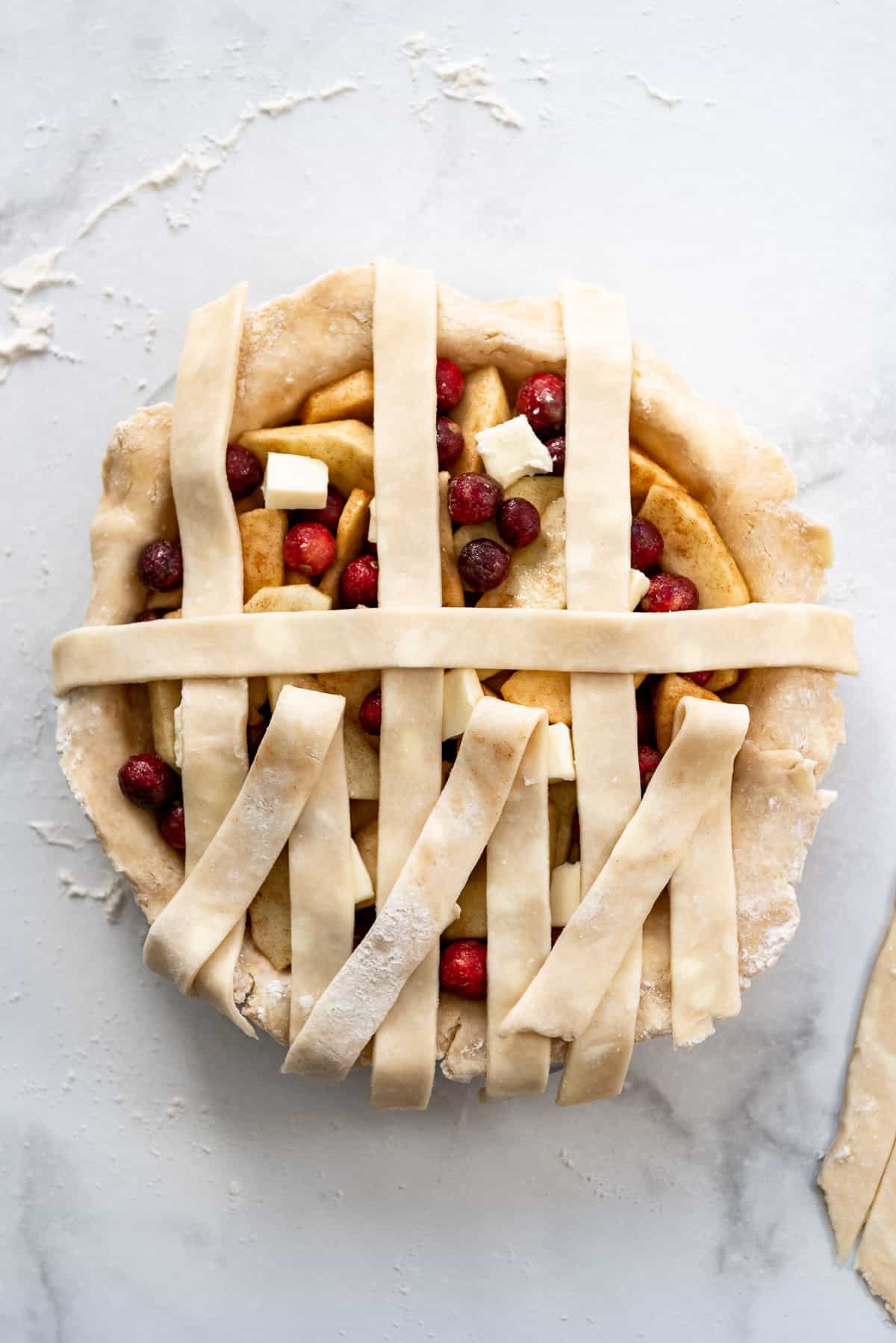 Adding a strip of pie dough perpendicular to weave a lattice crust.