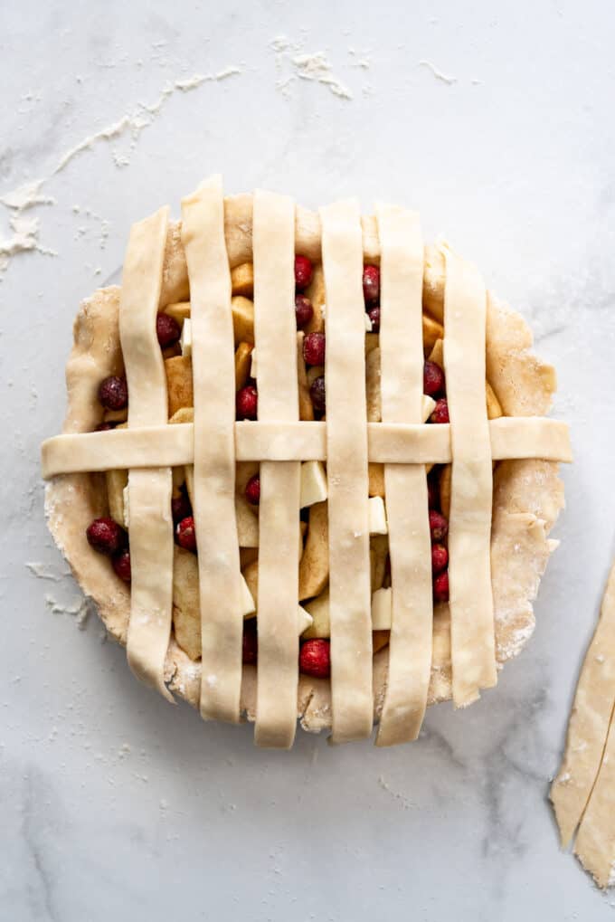 Replacing pie crust strips over perpendicular strips of dough.