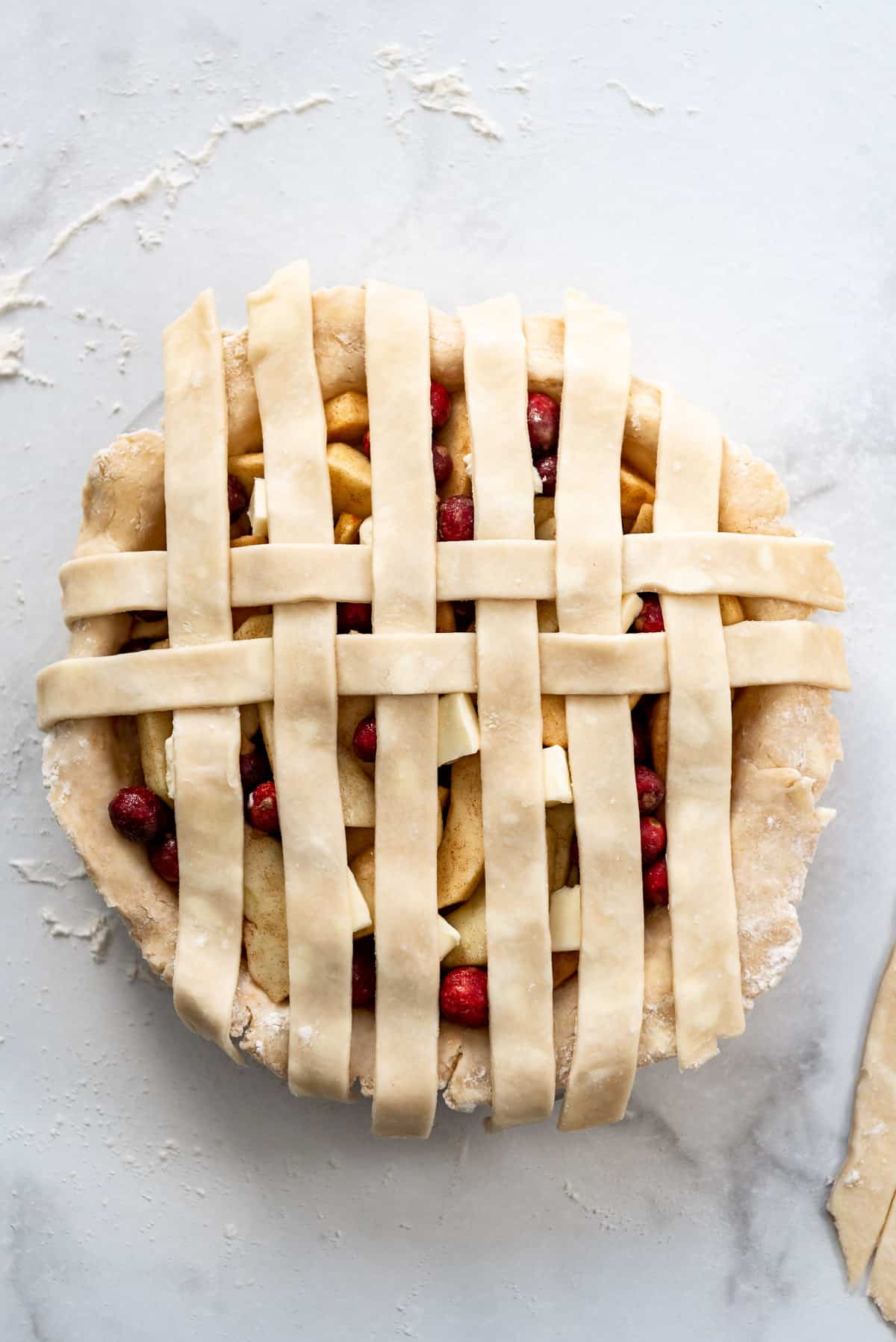 Another row of pie crust dough in place on top of a cranberry apple pie.