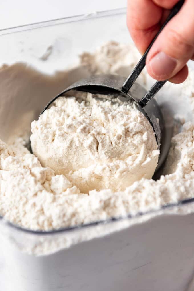 Scooping flour with a measuring cup.