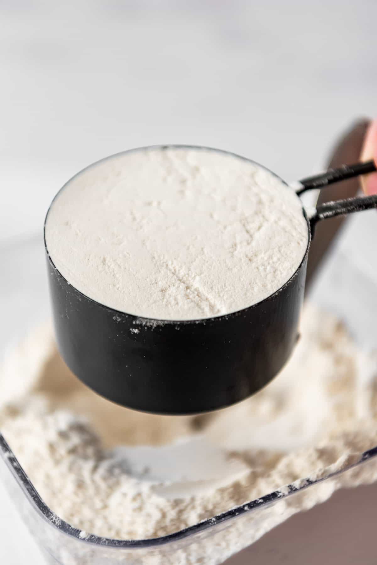 A measuring cup filled with flour and leveled off.