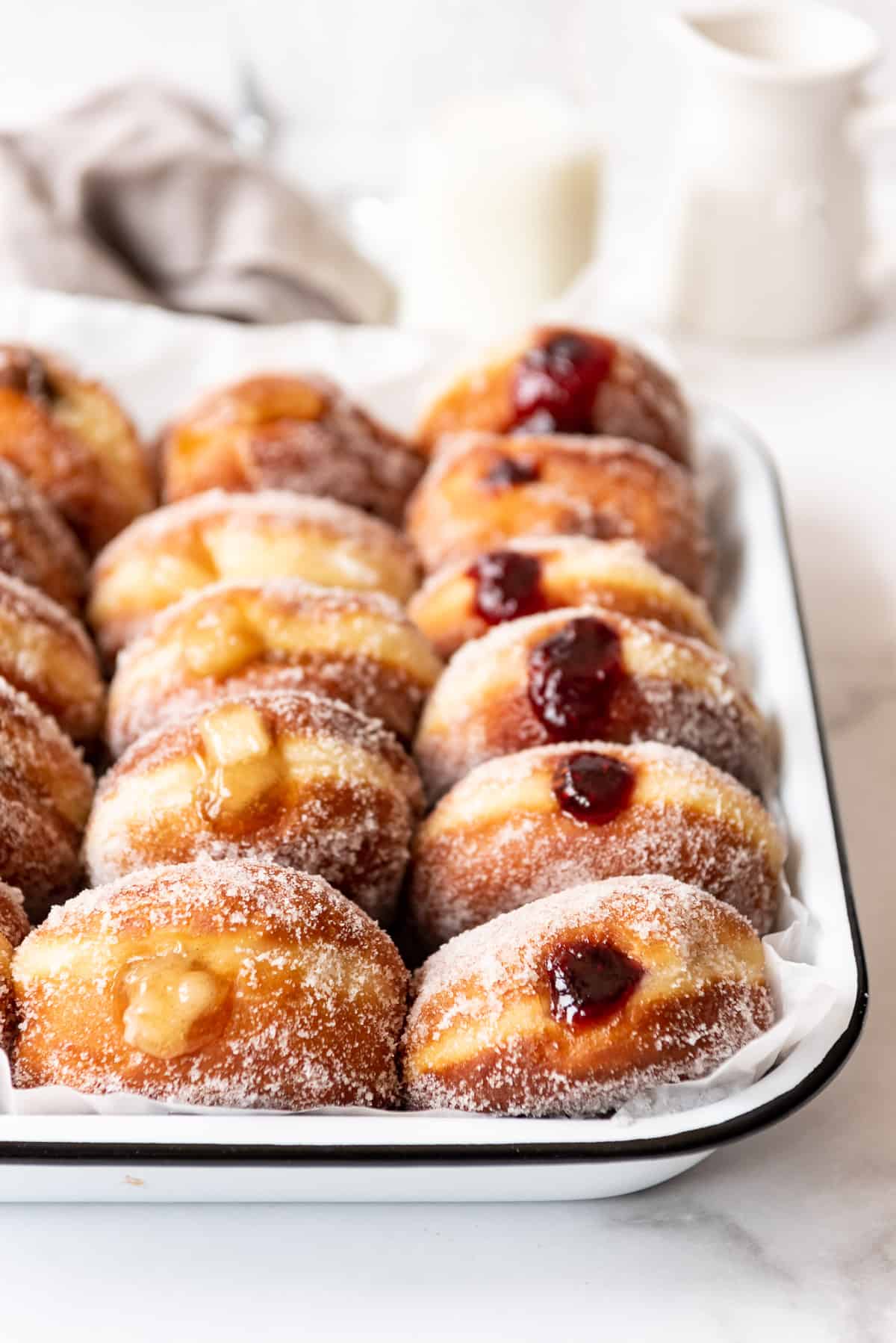 Rows of freshly filled donuts lined up against each other.