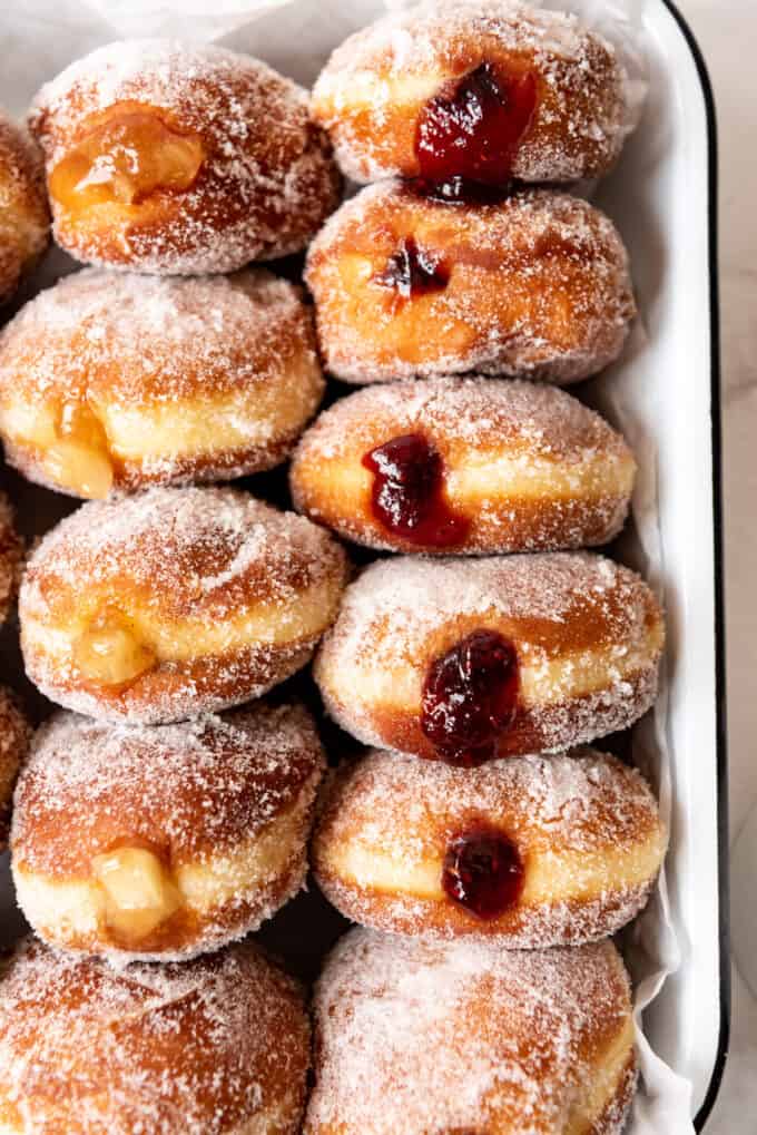 A close image of freshly made jelly donuts filled with raspberry jam and apple pie filling.