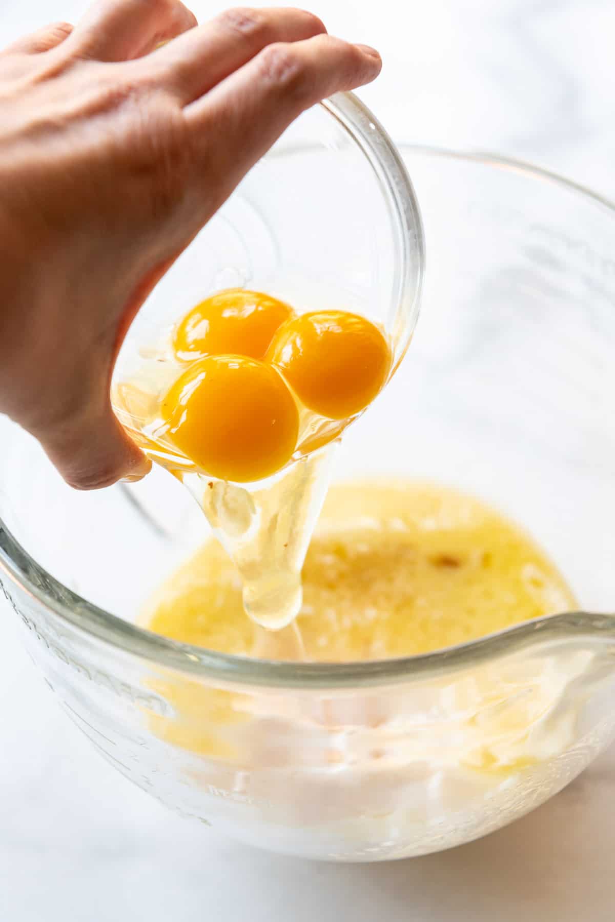 Adding eggs to an enriched yeast bread dough for making homemade donuts.