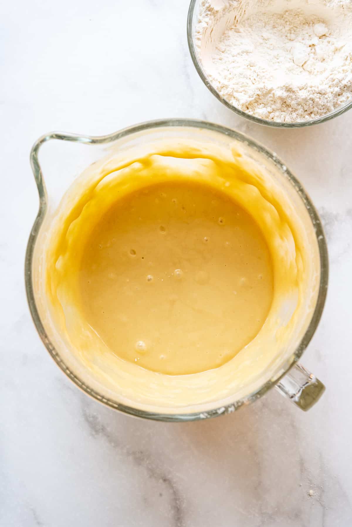 Enriched yeast, egg, flour, and butter mixture in a glass bowl.