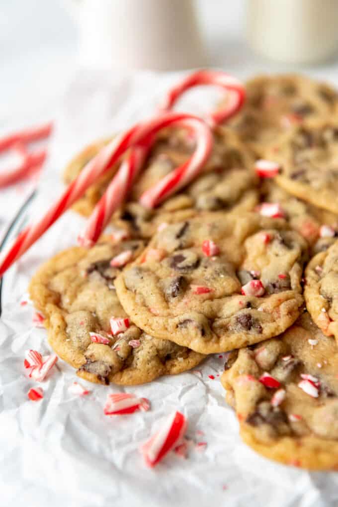 Chewy peppermint chocolate chip cookies with candy canes beside them.
