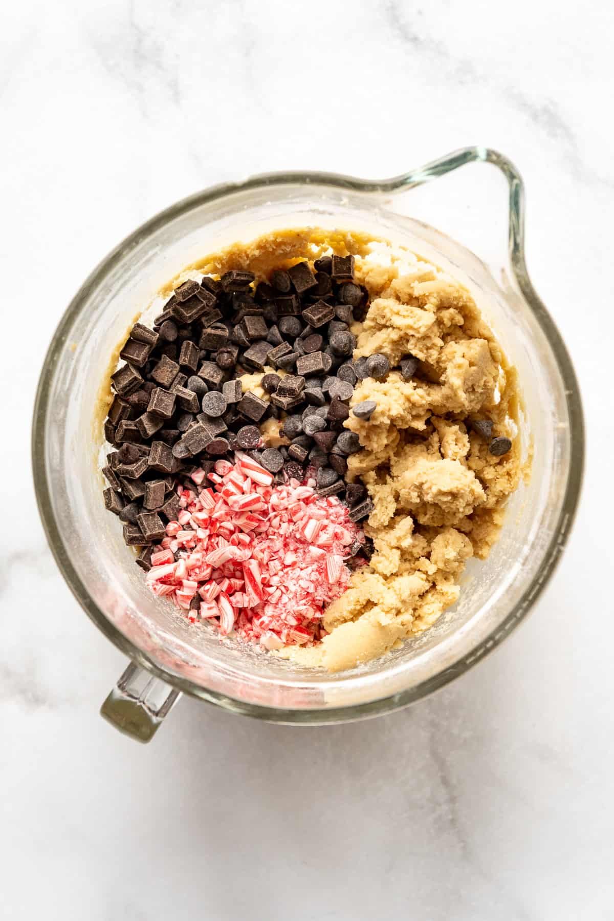 Adding chocolate chips and crushed candy canes to cookie dough.