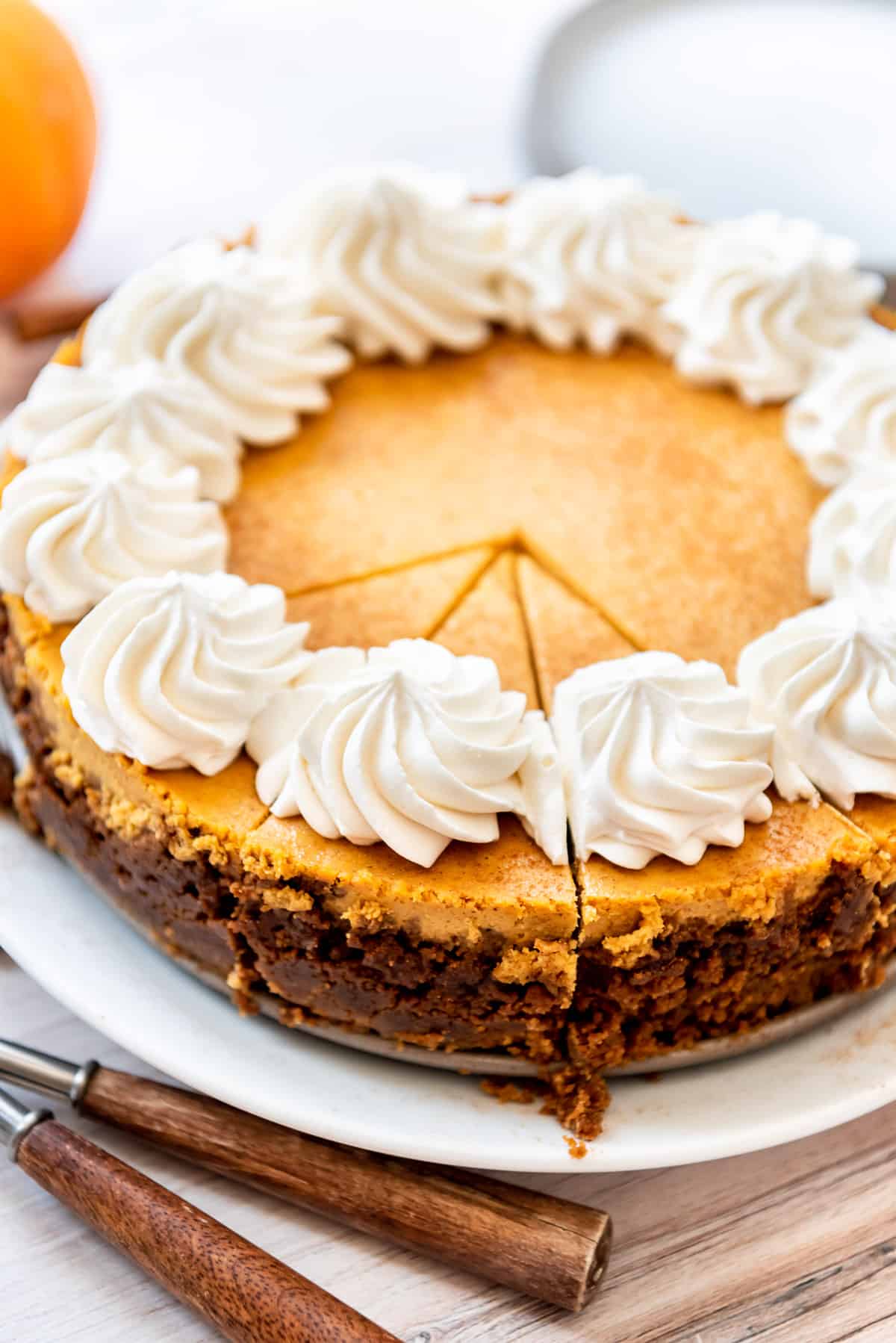 A sliced pumpkin cheesecake with swirls of whipped cream piped on top.