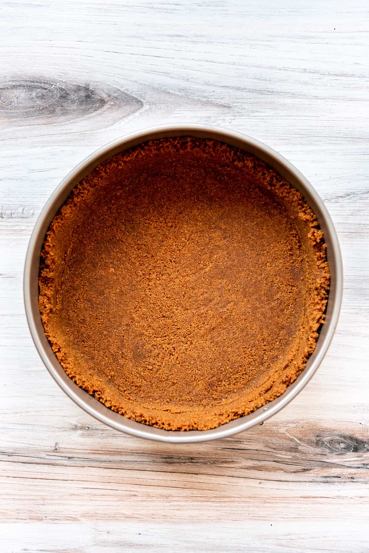 A biscoff cookie crust in a springform pan.