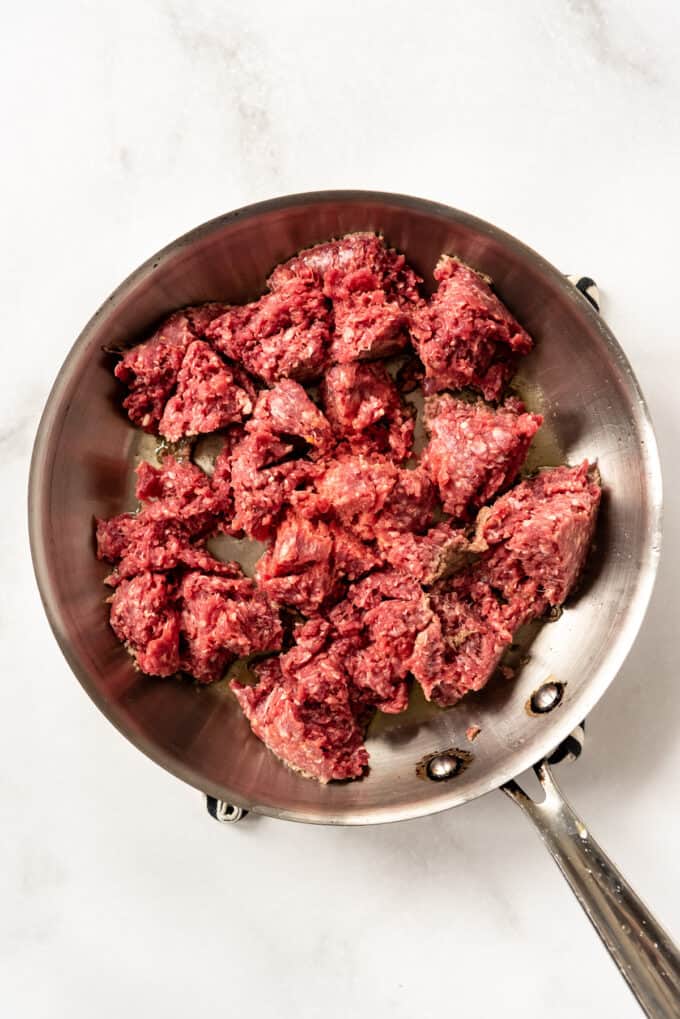 Broken up ground beef being browned in a large skillet.