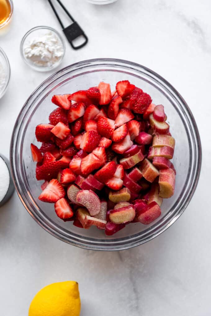 Fresh quartered strawberries and chopped rhubarb in a glass bowl.
