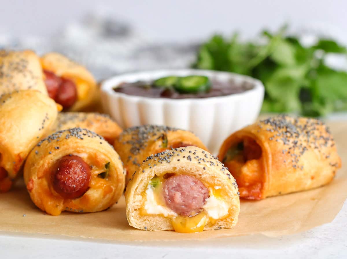 A pig in a blanket that has been cut in half to show the melted cheese inside.