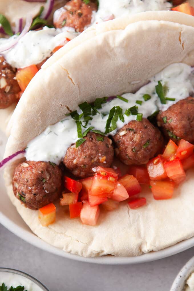 An easy gyro sandwich made with baked Greek feta meatballs, tzatziki sauce, and tomatoes.