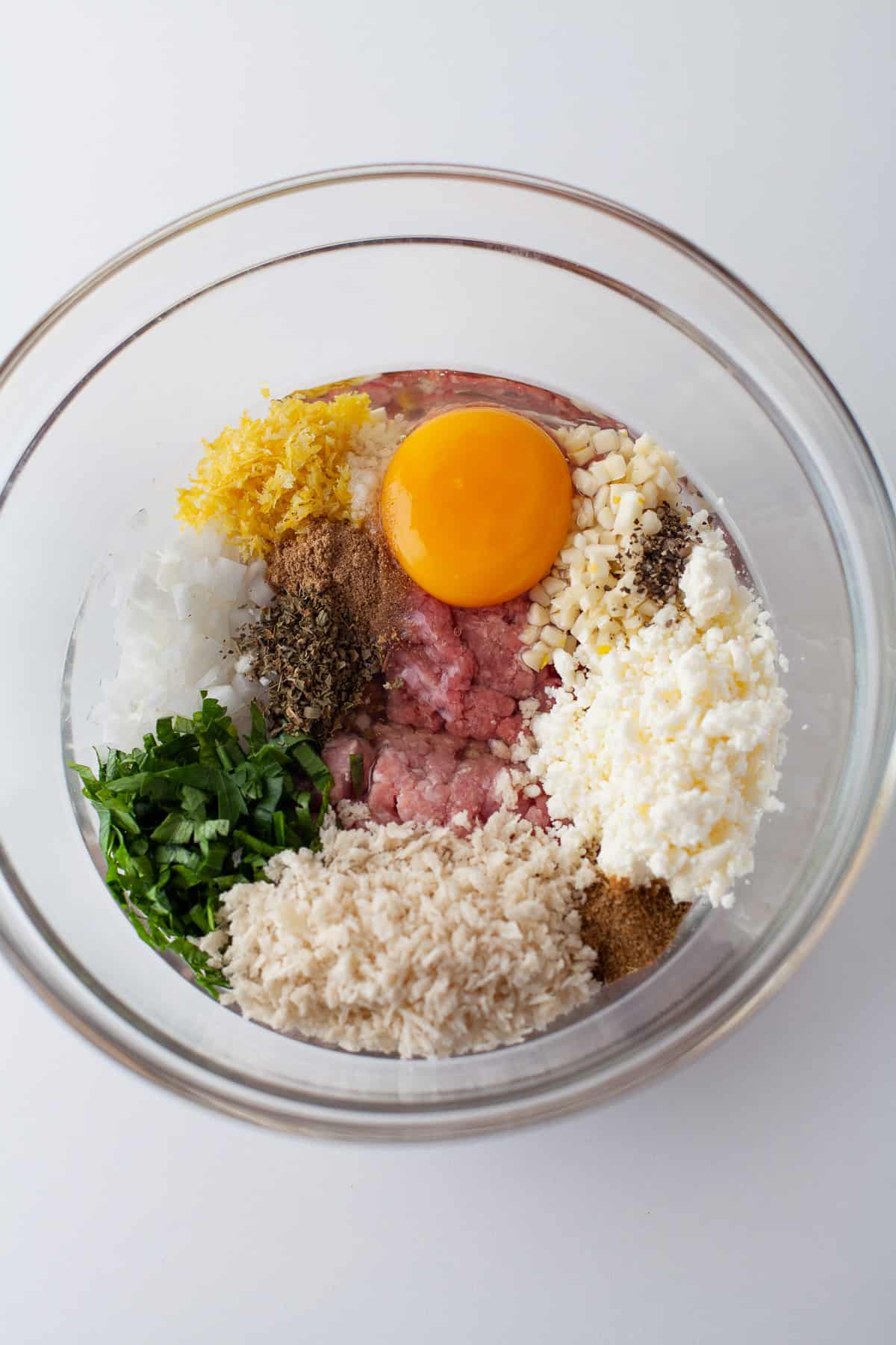 Greek meatball ingredients in a glass bowl.