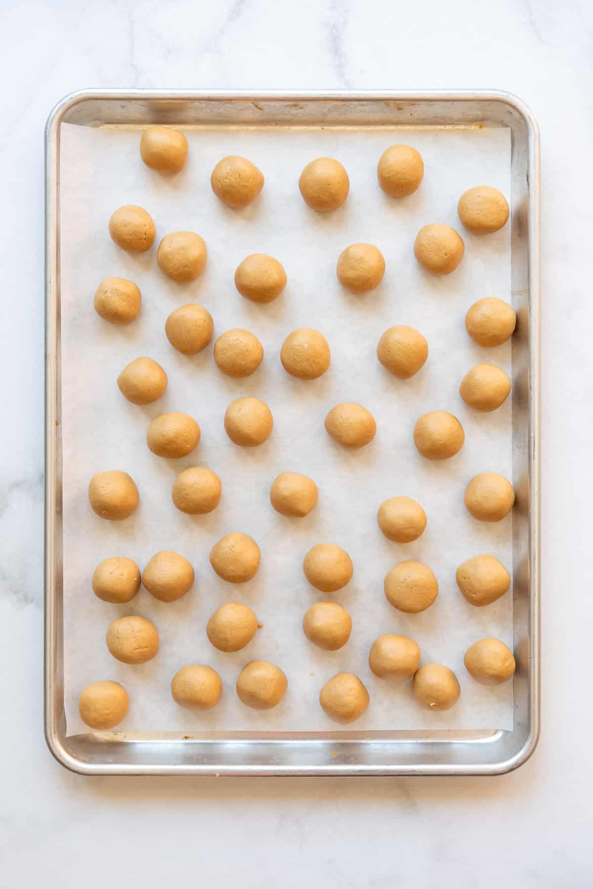 A baking sheet filled with the peanut butter centers of buckeyes candy before dipping.