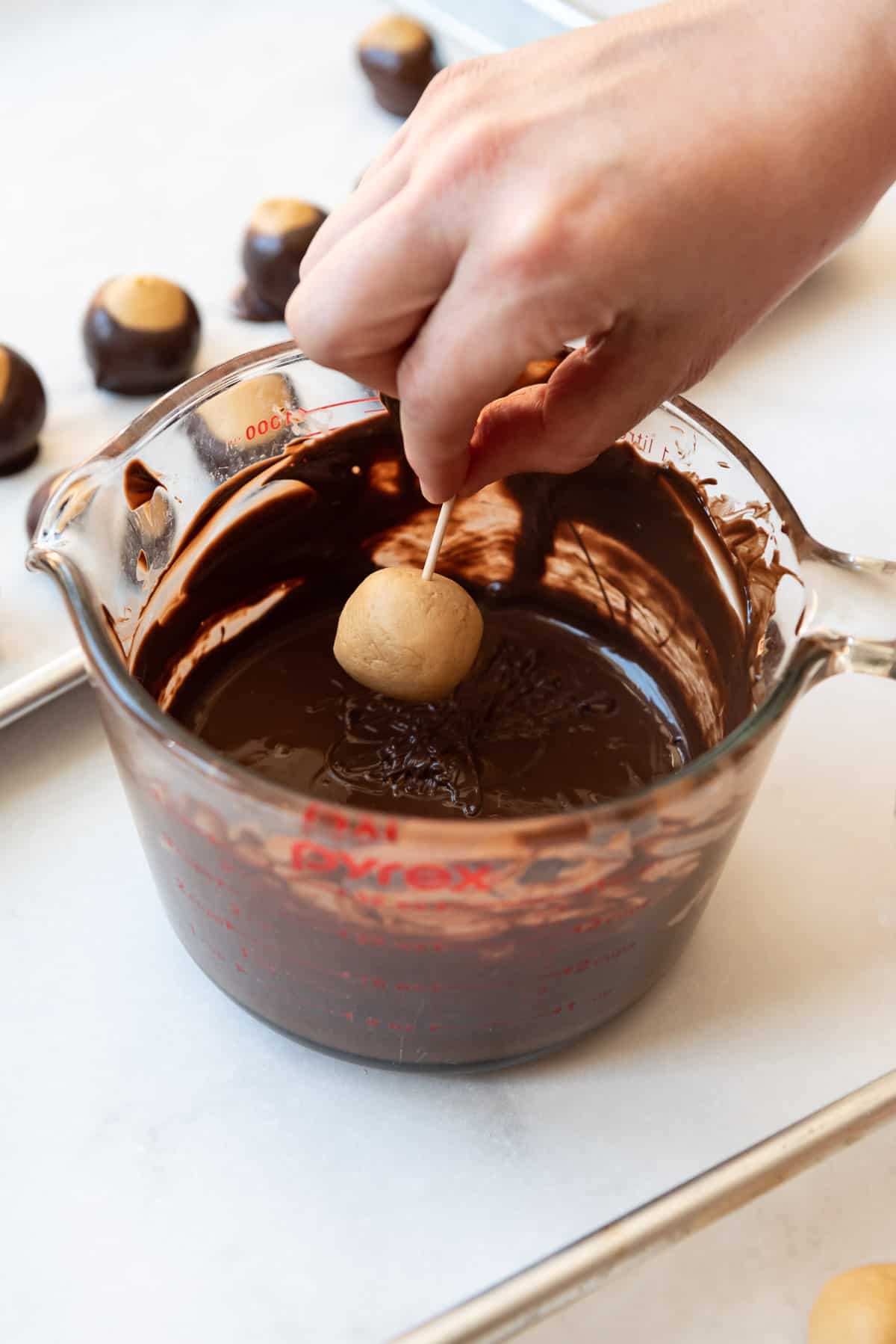 Dipping a ball of peanut butter dough into melted chocolate.