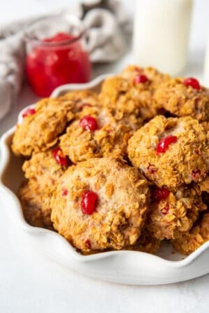 Stacked cookies covered in cornflakes with a piece of maraschino cherry baked into the top.