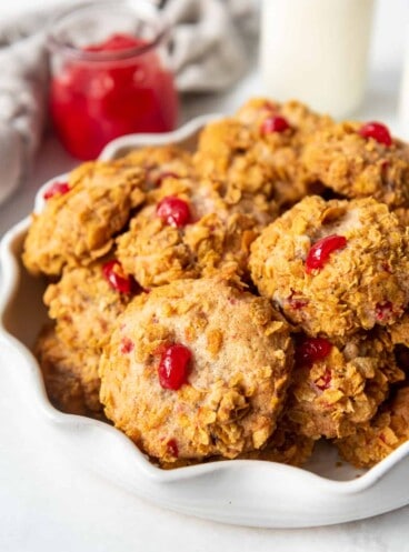 Stacked cookies covered in cornflakes with a piece of maraschino cherry baked into the top.