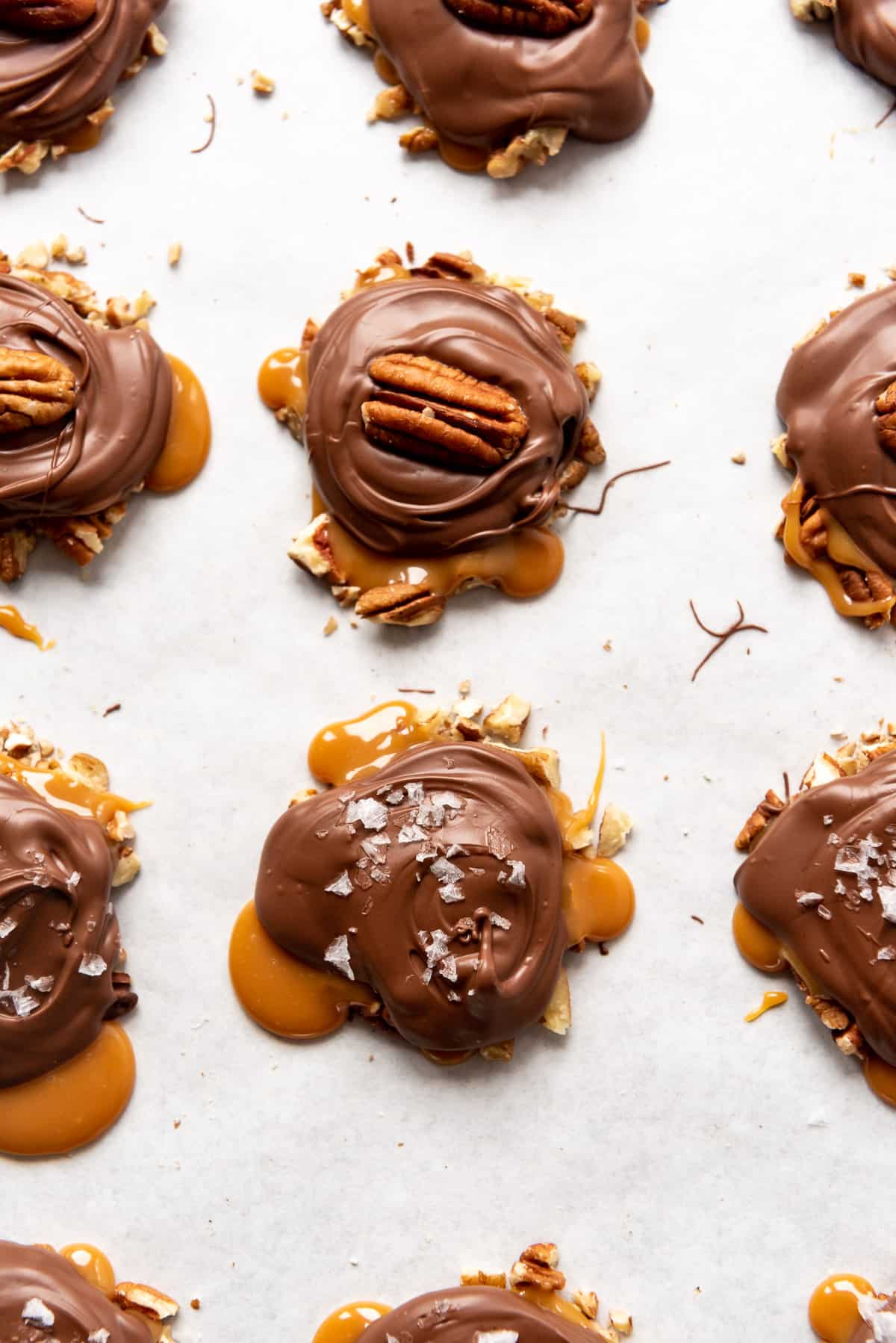 Caramel covered in chocolate over chopped toasted pecans.