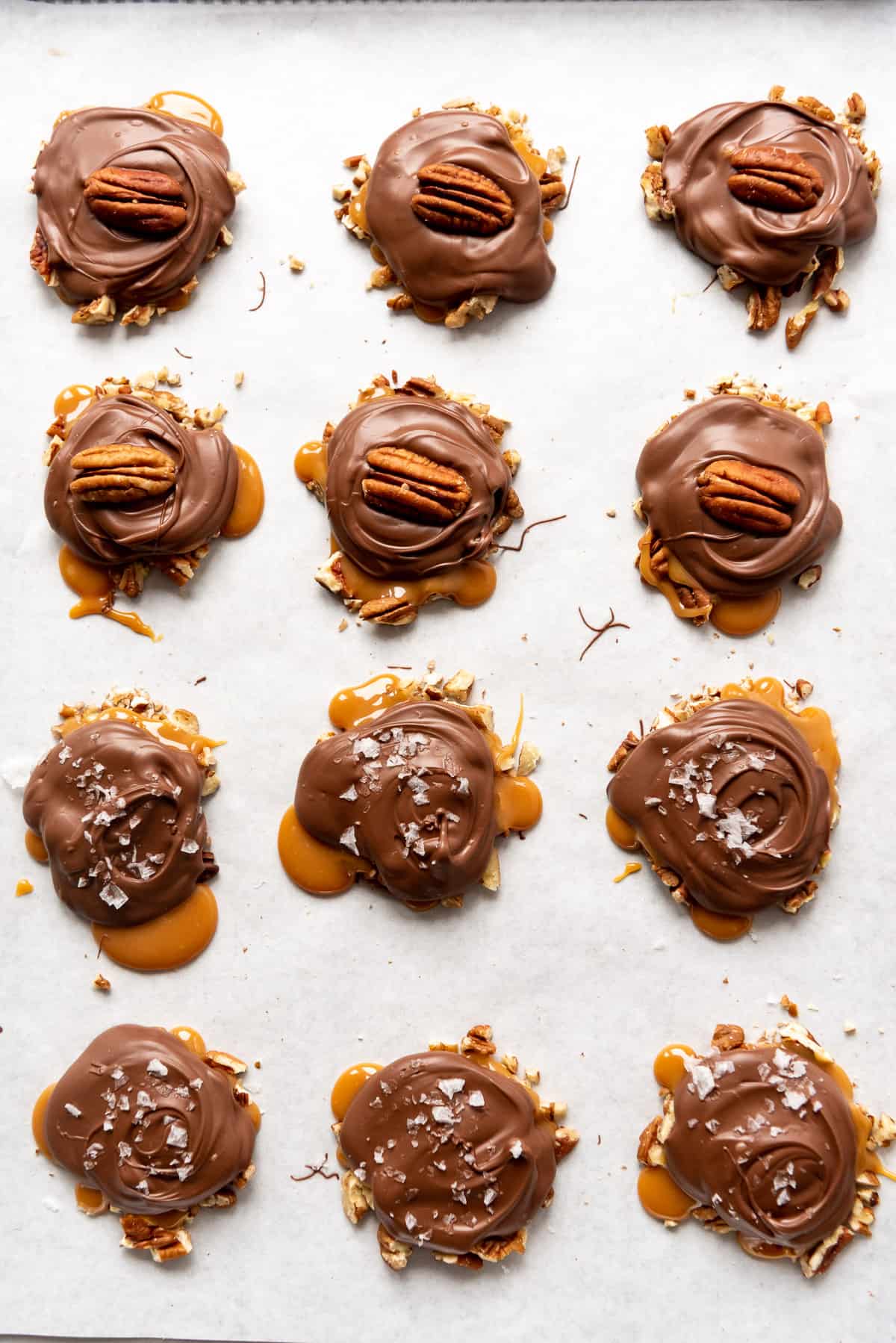 Rows of homemade turtles on a parchment lined baking sheet.