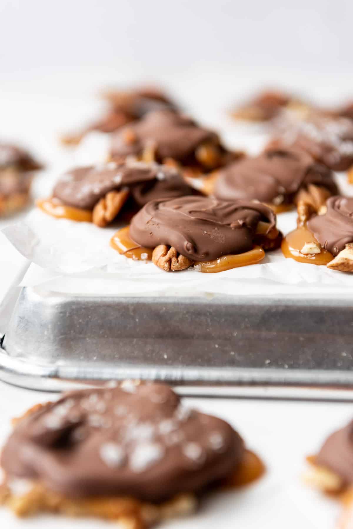 Easy homemade turtles candy on an overturned baking sheet with parchment paper on it.