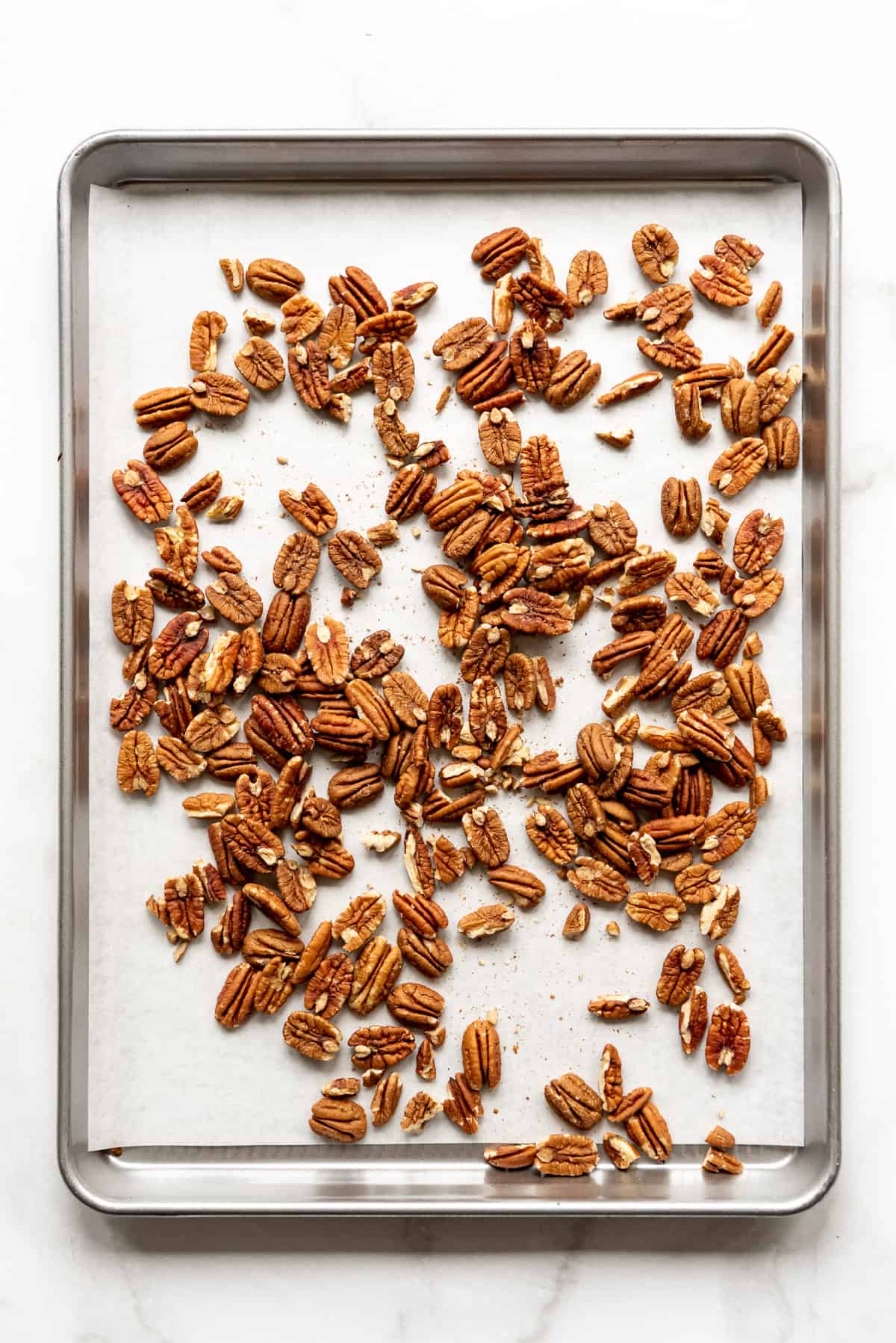 Whole pecans on a baking sheet for toasting.
