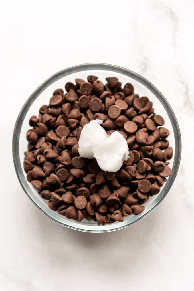 Chocolate chips in a glass bowl with coconut oil.