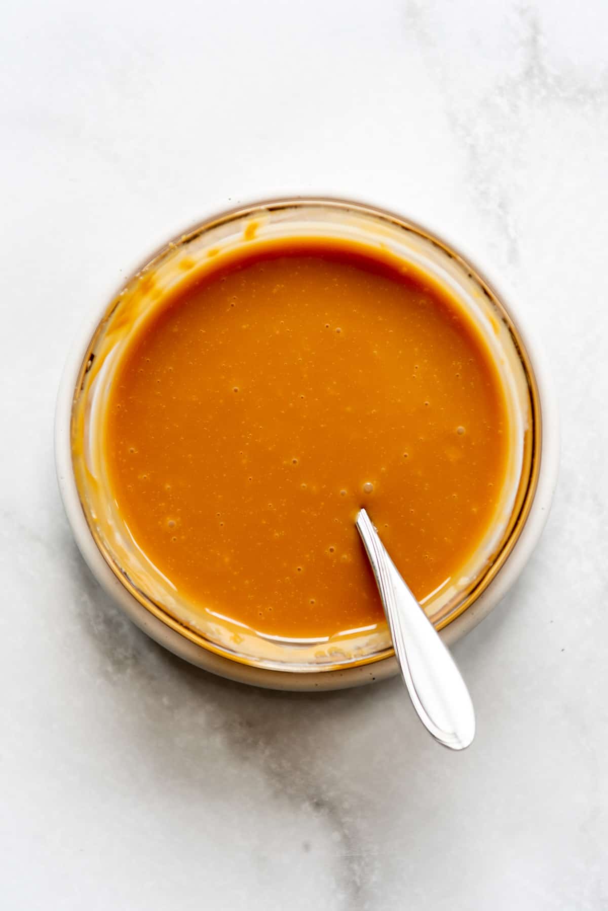 Melted caramel in a bowl with a spoon.