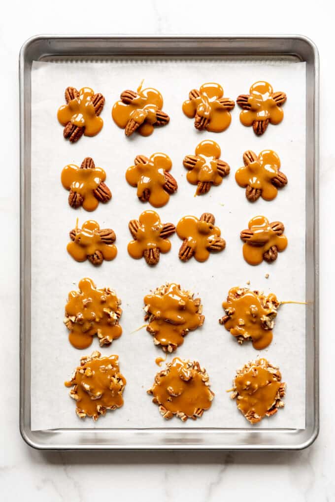 Piles of toasted pecans with caramel spooned over them.