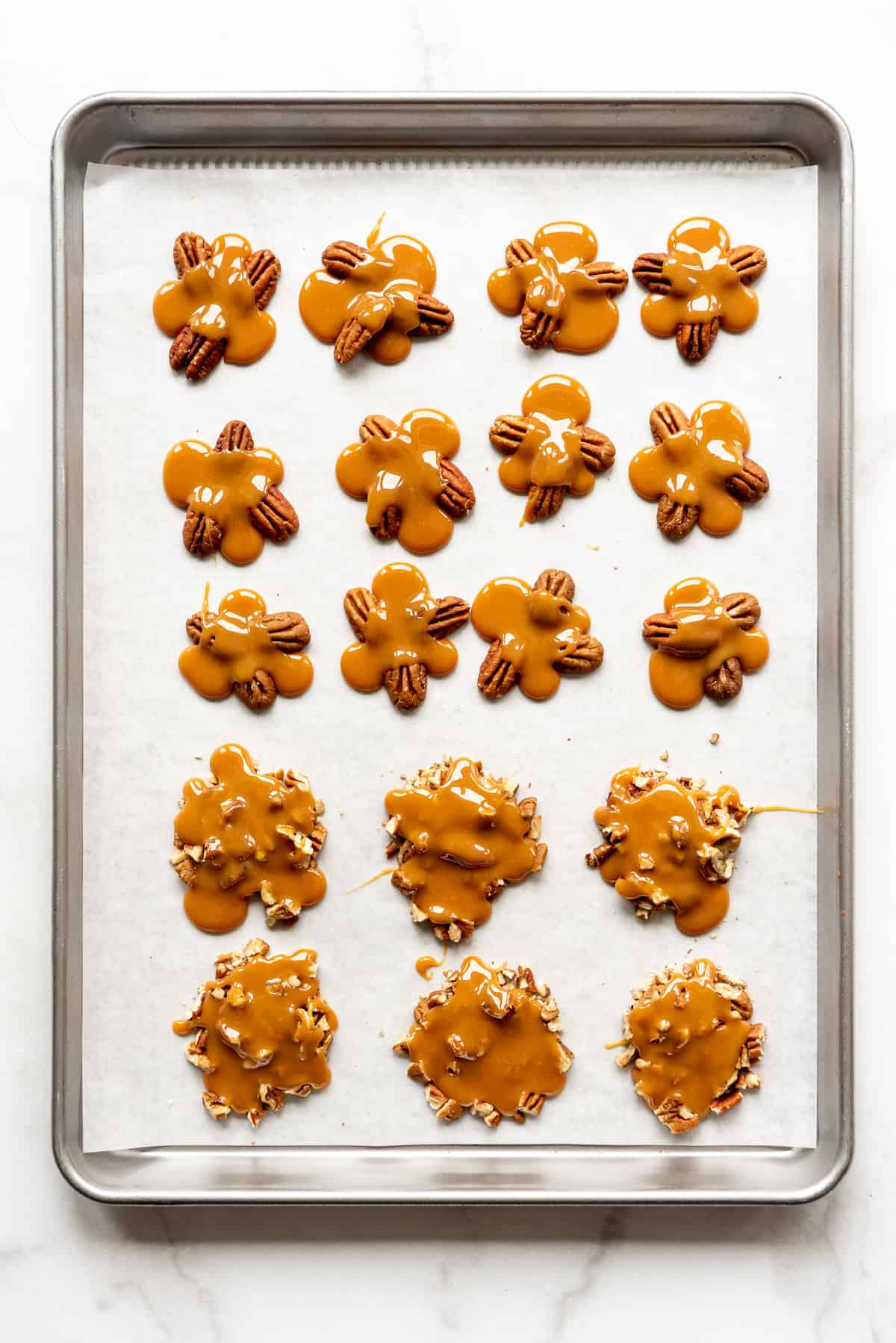 Piles of toasted pecans with caramel spooned over them.