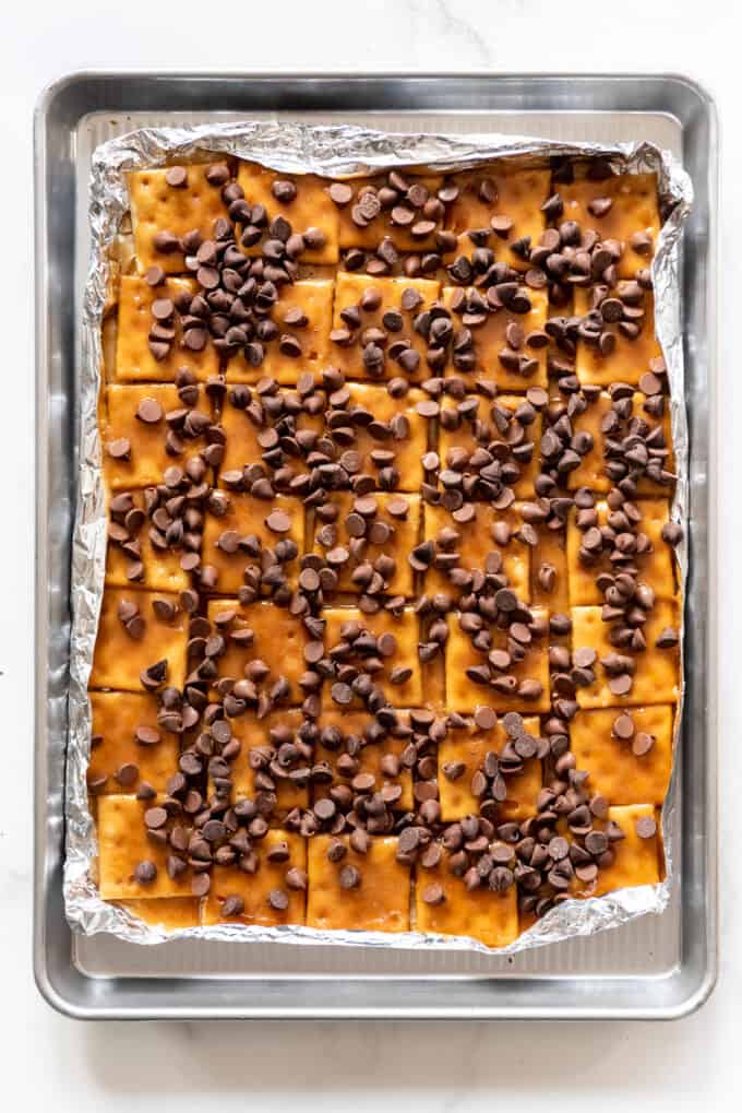 Chocolate chips sprinkled over hot saltine cracker toffee to melt.
